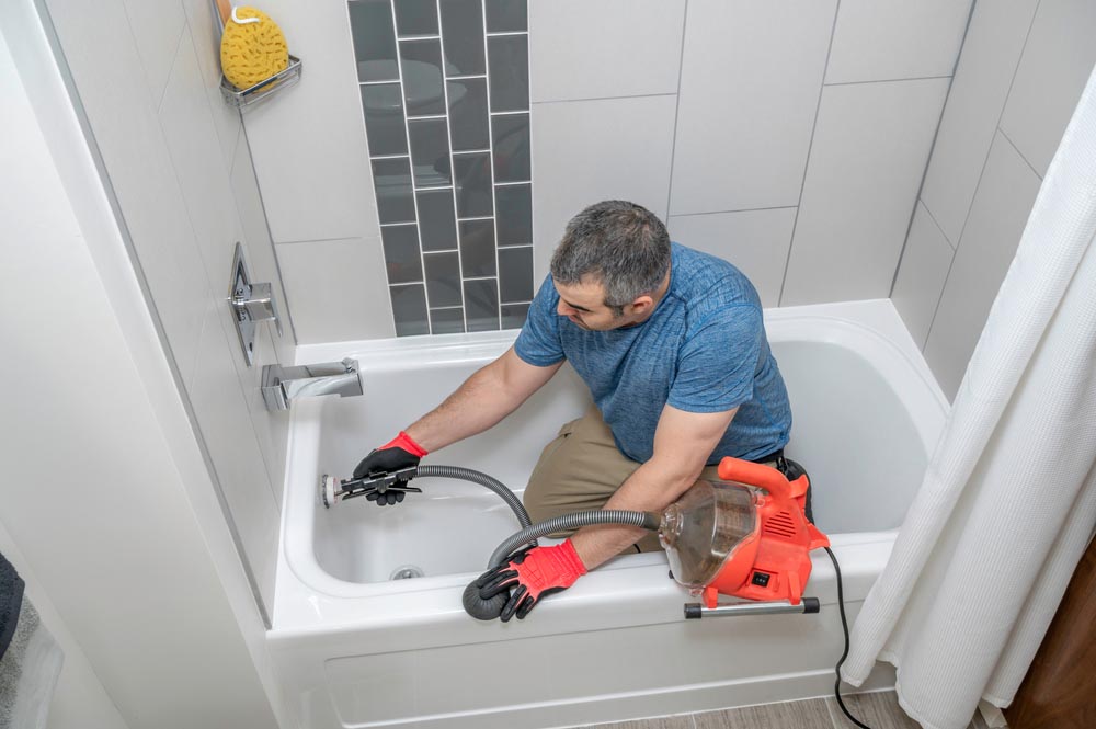 Plumber drain cleaning a bathtub with a plumbers snake Spokane, WA